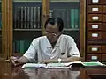 Un professeur avec un pin's Kim Il-sung et Kim Jong-il.