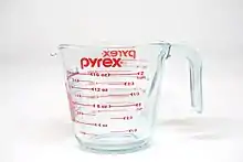 Verre doseur avec graduations et logo de la marque en rouge