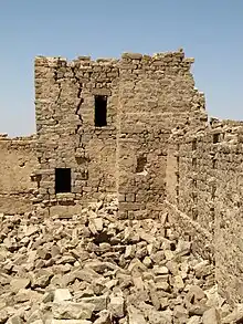 tour en ruine, murs en pierre ocre. Amas de pierres au sol