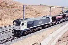 la photo couleur montre une locomotive bleu foncé à cabines blanches sur un train de ballast.