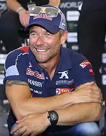 Photo de Sébastien Loeb vu de face en combinaison automobile.