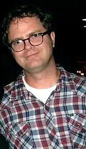 Photographie d’une homme avec des lunettes souriant.