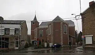 Édifice religieux en brique de style néo-roman. A gauche, une habitation.