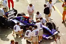 Vue en plongée d'une monoplace de Formule 1 entourée par des mécaniciens