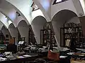 Intérieur des anciennes écuries avec aperçu des fenêtres trapézoïdales et des arcs paraboliques.