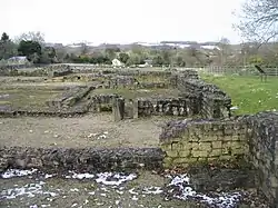 Photo de bâtiments en ruine dont ne subsiste quasiment que l'empreinte au sol, avec quelques pans de murs de hauteur réduite
