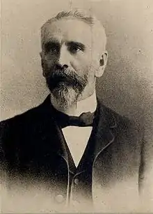 Photographie noir et blanc d'un homme en habit avec nœud papillon.