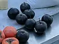 Poires gelées (noires) de l'Oussouri, forme consommée(en rouge, des kakis).