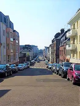 Cliché numérique couleur. Rue bordée d'immeubles d'habitation de trois étages du XXe siècle en enfilade.