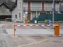 Photographie en couleurs de deux barrières relevables en position fermée à proximité d'une maison.