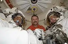 Photographie de trois hommes dont deux en scaphandre d'astronaute.