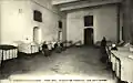 Photo en noir et blanc d'une salle bordée de lits avec des femmes  assises