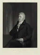 Un homme aux cheveux blancs et habillé en noir.