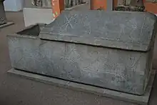 sarcophage en pierre couvercle à demi-soulevé. Divers motifs gravés : deux lions, un paon, un symbole christique, une fontaine