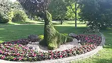 Au milieu d'un parterre de fleurs violettes, lui-même au milieu d'une pelouse très verte, se dresse la sculpture végétale d'une otarie, nez pointé vers le haut dans cette attitude typique de l'animal.