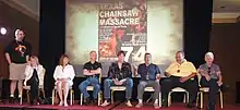 Photo d'un groupe de personnes assises dans un cinéma devant un écran projetant une affiche de film.