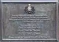 Plaque grise rectangulaire indiquant : «&nbsp;Près de cette localité le 16 décembre 1910 trois policiers de la "City of London Police" ont été tués en empêchant un cambriolage au numéro 199 Houndsditch. En souvenir des Sgt Robert Bentley, Sgt Charles Tucker, PC Walter C. Choat, que leur bravoure et leur sens de la fonction ne soient pas oubliés ».