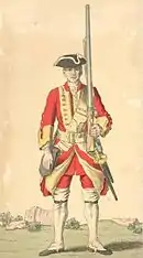 Uniforme rouge à pans relevés, tricorne noir, fusil