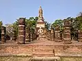 Grand wihan aux escaliers et sol en briques, aux colonnes en latérite avec en arrière-plan le chedi principal du temple sur un axe est-ouest