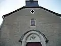 La façade de l'église avec une statue de la Vierge à l'Enfant protégée dans un coffret et une vitre.