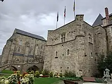 Vue de deux édifices anciens, une grosse tour carrée à droite et un autre bâtiment sur la gauche, les deux édifices étant séparés par un pont