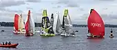 Des voiliers de course se suivent de manière groupée et affalent leur gennaker avant de passer une bouée