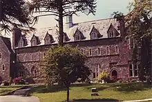 Façade d'un bâtiment en pierres, avec un arbre au premier plan.
