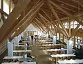 Local sous combles avec tables et chaises rigoureusement identiques et alignées.