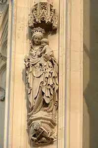 Tour nord, Beau Pilier, statue de la Vierge. À ses pieds, un homme joue du rebec<ref>Bourassé 1857, p.&nbsp;180