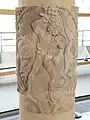 Photographe d'une colonne antique représentant un personnage près d'un arbre fruitier.