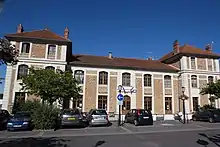 Vue d'un bâtiment en pierre de taille et meulière, pavillon central à 1 étage ; ailes à 2 étages.