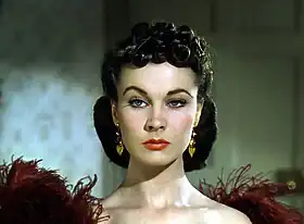 Une femme à l'épaule dénudée, avec une coiffure complexe. Elle lève un sourcil d'un air agacé.