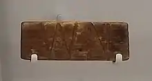 Morceau de bois gravé des lettres W et N.