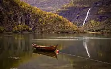 Photographie d'un lac d'où se reflète au loin une cascade et la vallée de Skjolden.