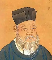 Portrait d'un vieil homme, qui porte une longue barbe blanche. Son visage est profondément ridé. Il porte un chapeau carré de couleur sombre.
